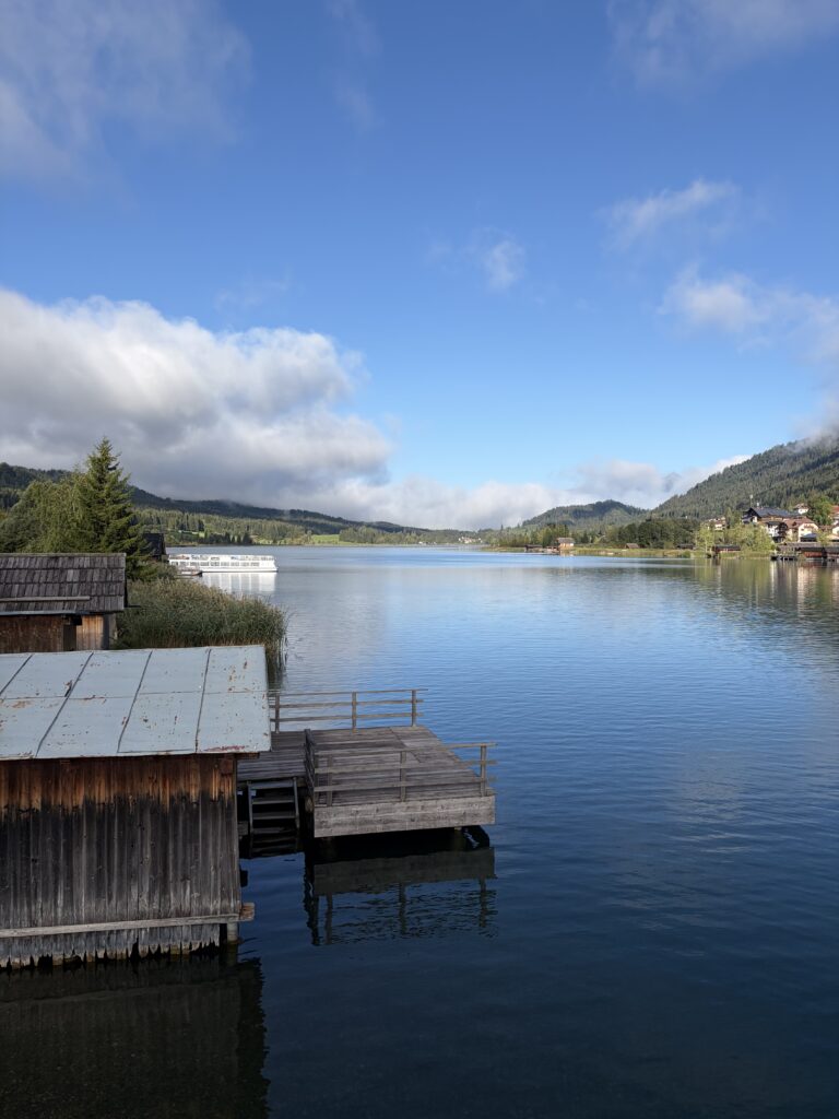 Ruhiger Weissensee mit Bootshäusern und Bergpanorama